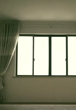 A window with curtains, morning light in an empty room.
